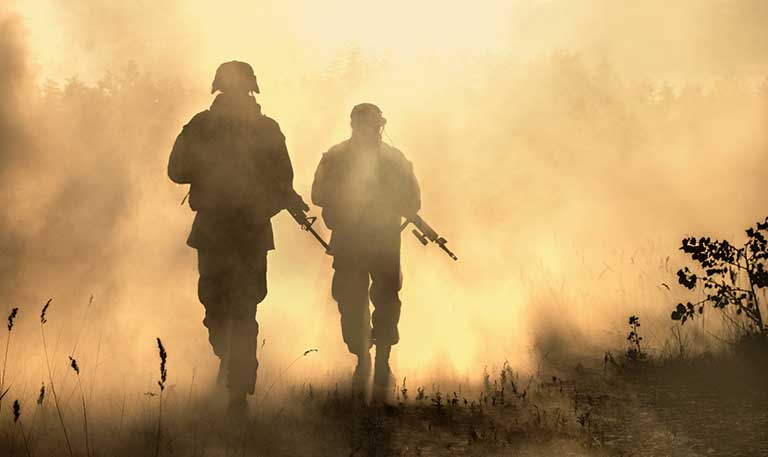 two soldiers walking through haze