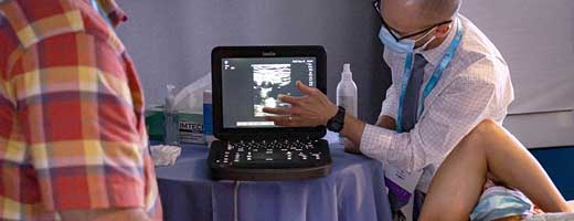 An instructor demonstrates an ultrasonography machine on a live model