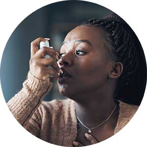 A woman uses an inhaler during an asthma attack